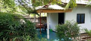a small white house with a porch with a table at Quiet Place villa with kitchen in Tangalle