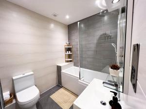 a bathroom with a toilet and a tub and a sink at Stylish 2 Bed Apt - Watford Gen Hospital - Watford FC - Professionals & Contractors Welcome in Watford