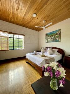 1 dormitorio con 2 camas y una mesa con flores en Rancho Saman, en Pereira