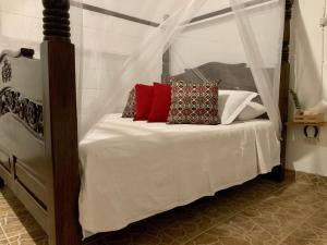 a bedroom with a canopy bed with red pillows at Rancho Saman in Pereira