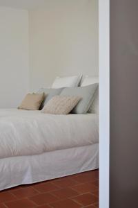 un letto bianco con cuscini sopra di Chambre d'hôte au Domaine Terre de Chênes a Saint-Paul-de-Baïse