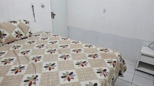 a bed with a quilt with flowers on it at Chalé 15 Porto dos Lençóis in Barreirinhas