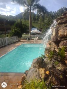 uma piscina com uma cascata ao lado de uma parede de pedra em Pousada nossa senhora em Aiuruoca