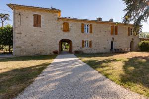 an external view of a large stone house with a driveway at Domaine de Laplan in Cézan