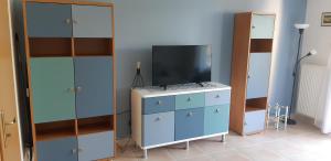 a living room with a tv and a dresser with a blue cabinet at Victoria Wave Apartman in Balatonőszöd