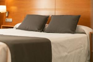 a bed with two pillows on top of it at Aparthotel Cal Marçal in Puig-reig