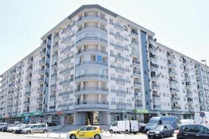 a large building with cars parked in a parking lot at Apartman Tanjuška in Podgorica +1 photo