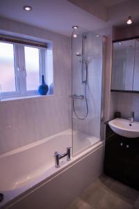 a bathroom with a tub and a sink and a shower at No 1 Kennington Court in Llandudno