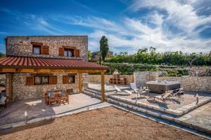 a stone house with a patio and a grill at Villa Stone Walls with Jacuzzi in Castellammare del Golfo