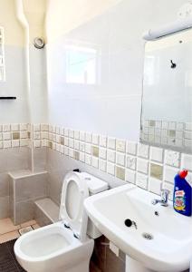 NYALI LUXURY APARTMENT في مومباسا: حمام ابيض مع مرحاض ومغسلة