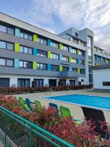 an apartment building with a swimming pool and chairs at Borics Apartman in Balatonföldvár