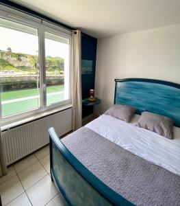 een slaapkamer met een bed en een groot raam bij L’Escapade de Michel - Vue Mer - Élégant in Dieppe