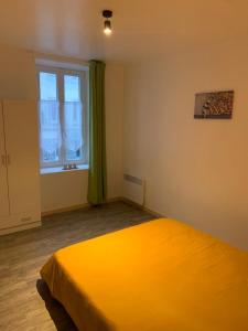 a bedroom with a large yellow bed with a window at L'appart du bourg - 4 chambres lits doubles - sur 2 niveaux - 2 salles de bain - séjour avec espace salon et cuisine équipée ouverte sur le séjour - in Beaumont-Hague