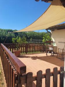 une terrasse en bois avec un banc et un parasol dans l'établissement Piccola casetta nel verde Mugello, à Barberino di Mugello