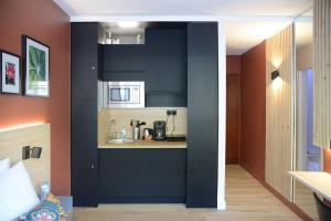 a kitchen with black cabinets and a sink in a room at Studio Chic Croix-Barbieux in Croix