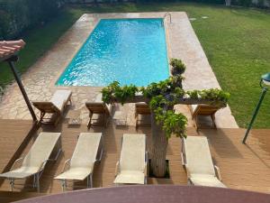 einen Pool mit Stühlen und einem Tisch mit einem Baum in der Unterkunft Relaxing Villa with Swimming Pool and Garden in Áyios Yeóryios