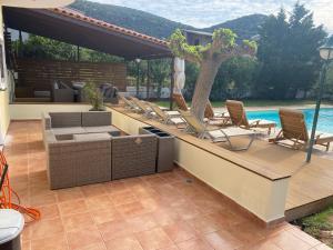 a patio with chairs and a tree next to a pool at Relaxing Villa with Swimming Pool and Garden in Áyios Yeóryios
