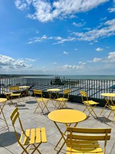 um grupo de mesas e cadeiras num pátio com vista para o oceano em Fort Road Hotel em Margate