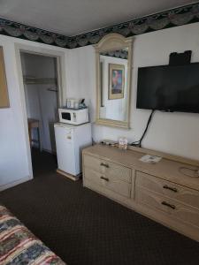 a living room with a television and a dresser with a microwave at Sands Motel in El Paso