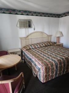 a hotel room with a bed and a table at Sands Motel in El Paso