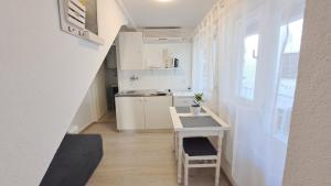 a small white kitchen with a table and a desk at Apartments Morning Sunshine in Korčula