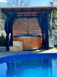 a hot tub under a wooden pergola next to a swimming pool at Black Horse in Pasłęk