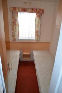 ein kleines Zimmer mit einem Fenster und einem Bett in der Unterkunft Plaża Pieniny - domki holenderskie in Czorsztyn