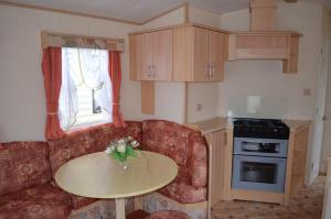 ein Wohnzimmer mit einem Sofa und einem Tisch in der Küche in der Unterkunft Plaża Pieniny - domki holenderskie in Czorsztyn