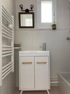 uma casa de banho branca com um lavatório e um espelho em Cabourg, appartement T2 accès direct mer em Cabourg