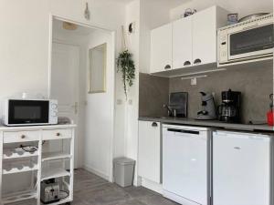 uma cozinha com armários brancos e um micro-ondas em Cabourg, appartement T2 accès direct mer em Cabourg