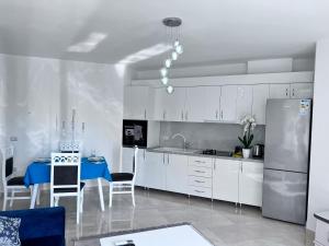 uma cozinha com armários brancos e uma mesa azul em White Luxury em Shkodër