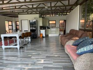 a living room with couches and a table and a kitchen at Sun Room (Studio) on the edge of the Harties dam. in Hartbeespoort
