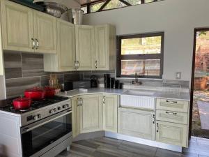 a kitchen with white cabinets and red pots on the stove at Sun Room (Studio) on the edge of the Harties dam. in Hartbeespoort