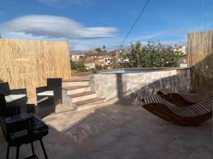 Un patio con dos sillas y una pared y escaleras. en Apartamento Home Paradaise, en Benajarafe