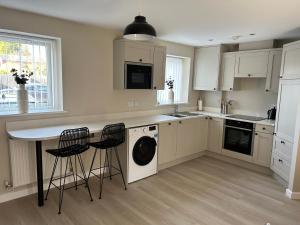 坎诺克Chapel Court Apartments的厨房配有白色橱柜和带凳子的桌子