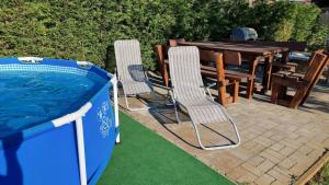 two chairs and a table next to a swimming pool at PanOli Apartmanház Nyíregyháza in Nyíregyháza