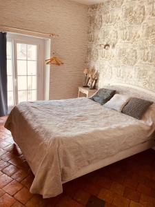a large bed in a bedroom with a stone wall at Hotel de la Sologne in Beaugency