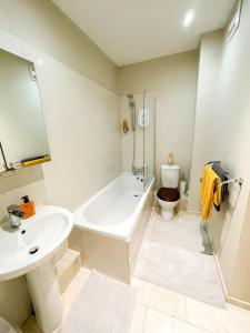 a bathroom with a sink and a tub and a toilet at Wilmot Guest House in London