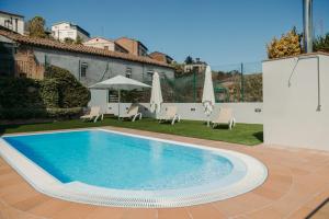 una piscina en un patio con sillas y sombrillas en Aparthotel Cal Marçal, en Puig-reig