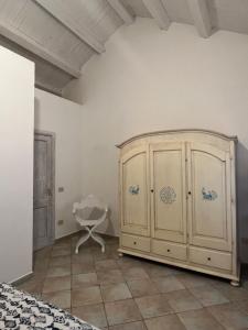 ein Schlafzimmer mit einem großen Holzschrank und einem Stuhl in der Unterkunft Appartamento il Caracolo a Cala Francese in La Maddalena