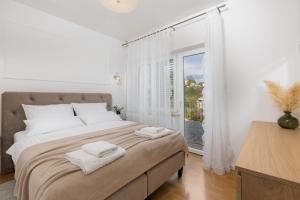 a white bedroom with a large bed and a window at Apartman Marina in Vrbnik