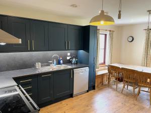 a kitchen with black cabinets and a kitchen table at Ben View in Torridon