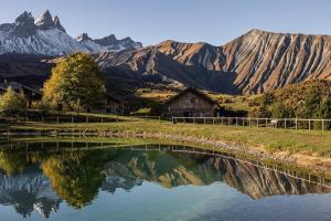 a reflection of a house in the water with mountains at Chalet d'Albiez in Albiez-Montrond