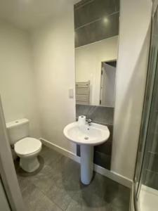 Baño blanco con aseo y lavamanos en Extra large 6 bed 7 bath townhouse in Manchester, en Mánchester
