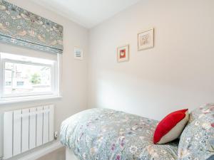 a bedroom with a bed with a red pillow and a window at Annes Cottage in Strines