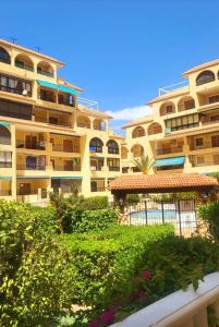 a large yellow building with a garden in front of it at Apartamento Luna Blanca, La Mata, 300 m from the sea and sandy beach plus swimming pool in La Mata