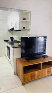 a kitchen with a flat screen tv on a wooden entertainment center at La Lucia Sleepover in Durban