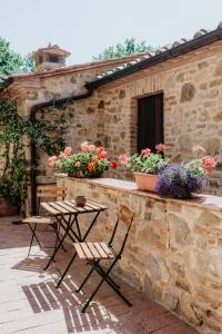 einen Tisch und zwei Stühle auf einer Terrasse mit Blumen in der Unterkunft Borghetto Poggio Bianco in Radicondoli
