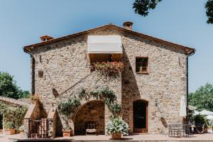 a stone building with flowers in front of it at Borghetto Poggio Bianco in Radicondoli