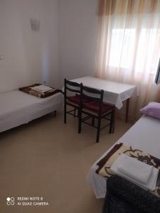 a room with two beds and a table and chairs at Dax in Ulcinj